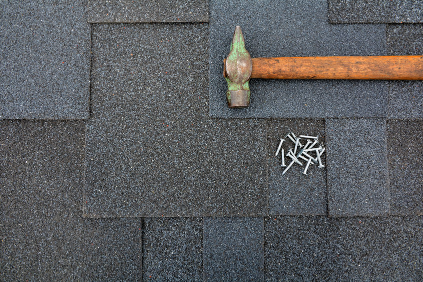 Hammer and nails on a shingle roof