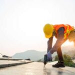 A worker in protective gear works on a commercial roof