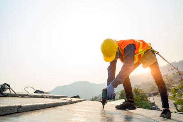 A worker in protective gear works on a commercial roof