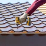 A man installs roofing shingles on a new roof