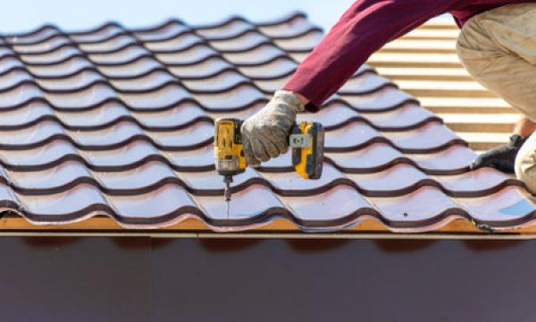 A man installs roofing shingles on a new roof